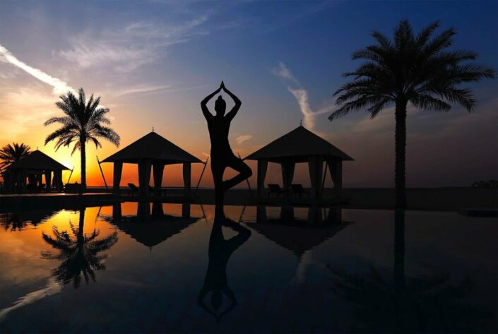Yoga am Pool am Abend bei Sonnenuntergang